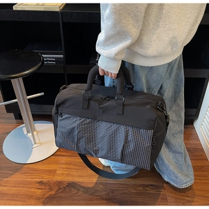 Detail of waterproof nylon travel bag featuring gray grid pattern and reinforced handles