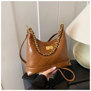 Détail d'un sac bandoulière marron matelassé avec fermoir rotatif en métal doré chic
