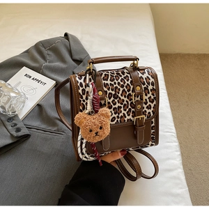 Close-up of leopard print backpack with brown leather patchwork and plush bear charm