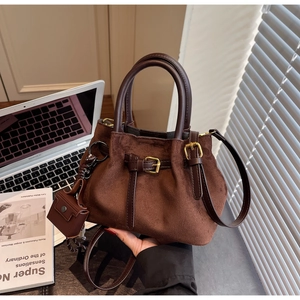 Close-up of brown suede crossbody bag with leather handles and gold metal hardware