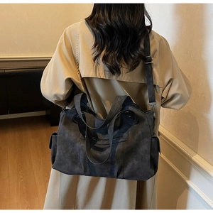 Detail of dark grey large tote bag with adjustable strap worn with khaki trench coat