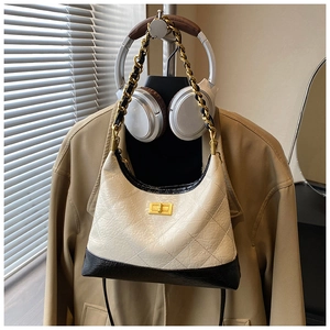 Détail du sac bandoulière en cuir matelassé beige avec base noire et bandoulière chaîne