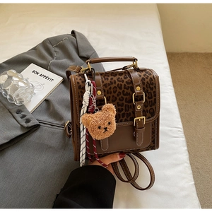 Close-up of leopard print backpack with faux fur bear charm and golden metal hardware