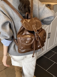 Retro brown faux leather backpack with white stitching and double front pockets on model