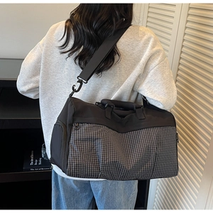 Back view of model wearing a large black and white checkered travel bag with shoulder strap