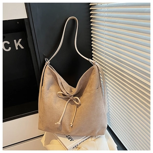 Detail of khaki suede bucket bag featuring elegant drawstring bow and vintage aesthetic