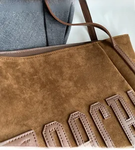 Detailed macro view of dark coffee suede fabric texture and stitched letter design