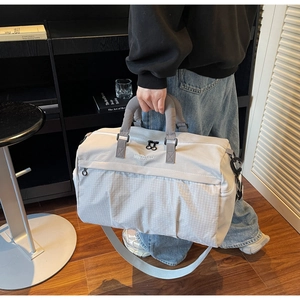 Detail view of reinforced padded handles and adjustable strap on light gray travel bag
