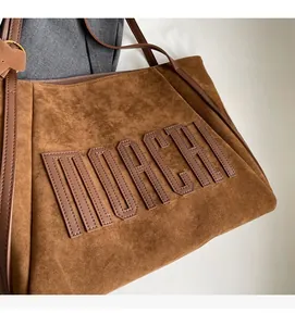 Detail of embossed MOACHI logo and premium suede texture on brown tote bag