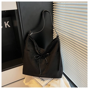 Close-up of minimalist black matte hobo bag featuring a decorative leather bow detail