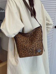 Sac hobo imprimé léopard avec bandoulière en cuir porté à l'épaule par un mannequin