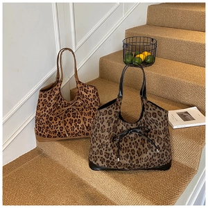 Détails de sacs fourre-tout léopard marron et gris avec nœuds posés sur l'escalier