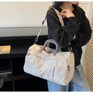 Detail of grey travel bag with checkered pocket and adjustable strap on a model