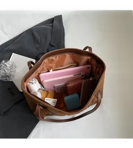 Top view of spacious brown tote bag interior holding tablet, umbrella and essentials