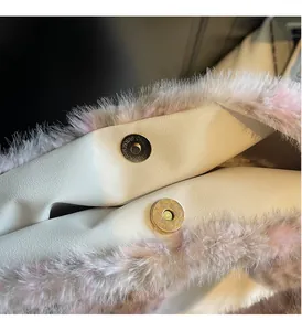 Detail of gold magnetic snaps and pink faux fur trim on a white plush tote bag