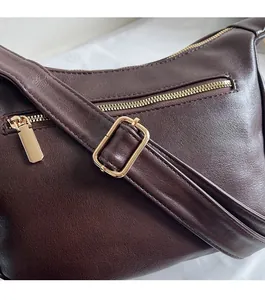 Detail of adjustable shoulder strap with gold metal buckle on dark brown dumpling bag