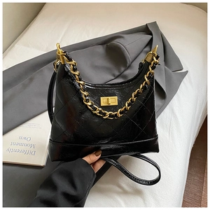 Détail du sac hobo en cuir matelassé noir avec chaîne dorée et fermoir pivotant