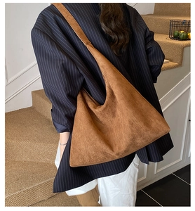 Große braune Wildleder-Tragetasche von Model auf Treppe im Hobo-Stil präsentiert