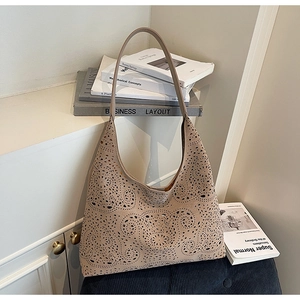 Detail shot of laser-cut floral patterns on beige tote bag with shoulder straps