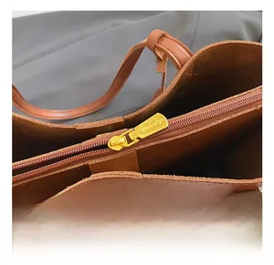 Close-up of golden metal zipper closure on a vintage brown leather tote bag detail