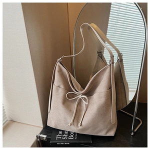 Detail of beige suede tote bag with adjustable shoulder strap and drawstring bow