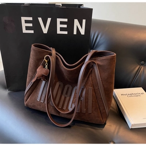 Detail of dark brown suede tote bag featuring 3D embroidery and leather elephant charm