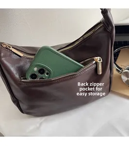 Close-up of dark brown hobo bag back zipper pocket with smartphone inside