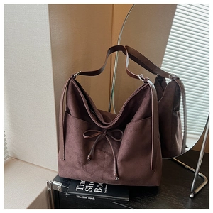 Detail of dark brown faux suede tote bag featuring a decorative bow drawstring and soft texture