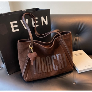 Detailed macro view of dark brown suede tote bag with stitched MORCHI leather lettering
