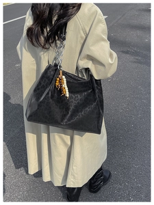 Detail of black leopard print tote bag with silver chain strap and beaded tassel decor