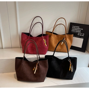 Detailed view of four suede tote bags in assorted colors with decorative beaded tassels