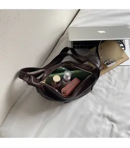 Spacious interior of dark brown leather hobo bag holding a tablet and cosmetics