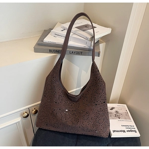 Detailed view of dark brown hollow-out suede tote bag with laser-cut patterns