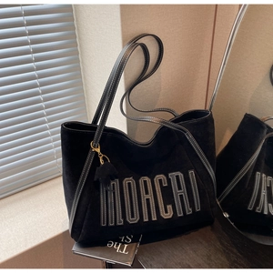 Close-up of black suede tote bag featuring white contrast stitching and MOACHI logo