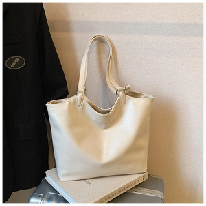 Creamy white leather tote bag on travel luggage with professional suit background