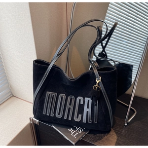 Detail of black suede tote bag with white contrast stitching and MOACAI letter patch