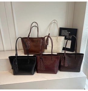 Five large vintage tote bags in various colors with elegant silk scarves on a stone display