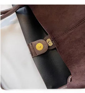 Close-up of golden magnetic clasp on a premium coffee suede and black leather tote bag