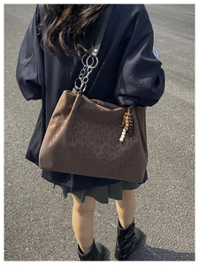 Detail of dark brown leopard print suede tote bag with metal chain and beaded charm