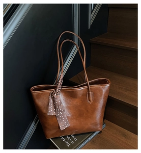 Close-up of vintage brown leather tote bag with elegant polka dot silk scarf detail