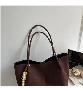 Detail of dark brown faux suede tote bag on a desk with beads and professional accessories