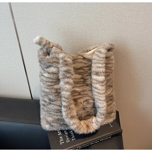 Detail of plush faux fur tiger stripe tote bag on a design book in soft lighting