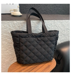 Close-up of black quilted nylon tote bag with rhombic pattern and soft padded double handles