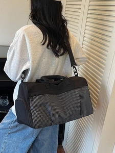 Large waterproof black travel bag with grey checkered detail shown on shoulder