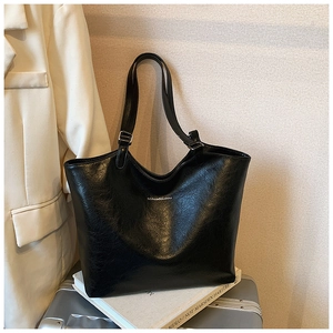 Detail of black large tote bag with oil wax texture and thin shoulder straps