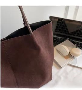 Close-up of dark brown suede tote bag with soft fabric texture and sturdy round handles