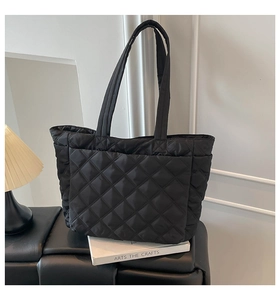 Detail of black quilted nylon tote bag featuring classic diamond stitching and side pocket