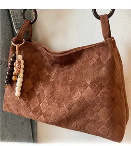 Detailed macro view of brown vintage suede shoulder bag with embossed diamond lattice patterns