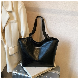 Detail of black glossy crinkled leather tote bag on silver suitcase for business travel
