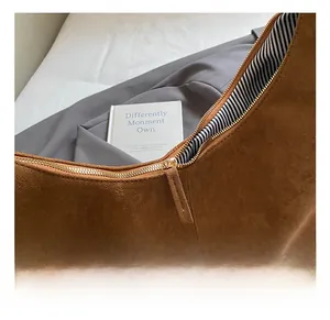 Nahaufnahme von goldenem Reißverschluss und Streifenfutter auf brauner Wildledertasche